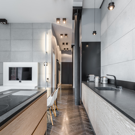Functional kitchen with black long worktop and ceiling lightsの写真素材