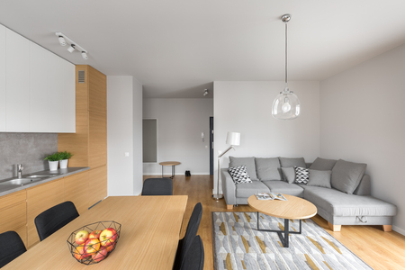 Modern open space dining room with long rectangular table and grey big corner sofa の写真素材