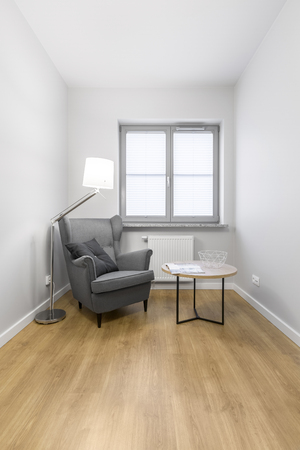 Grey armchair with small round table and modern lamp on the wooden floorの写真素材