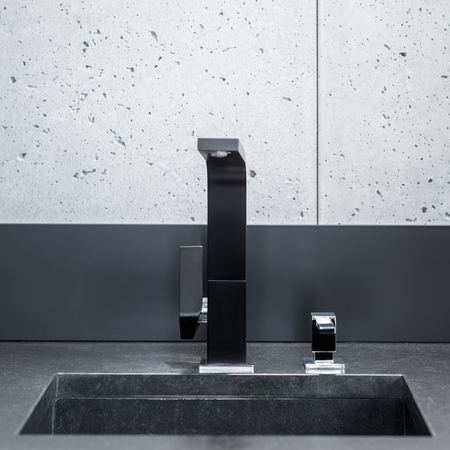 Black kitchen worktop, sink with modern tap and grey wall tilesの写真素材
