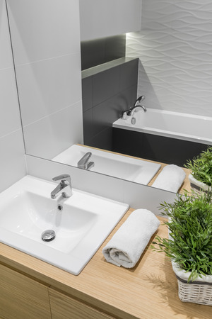 Modern bathroom with basin cabinet, mirror, bathtub, textured wall decorの写真素材