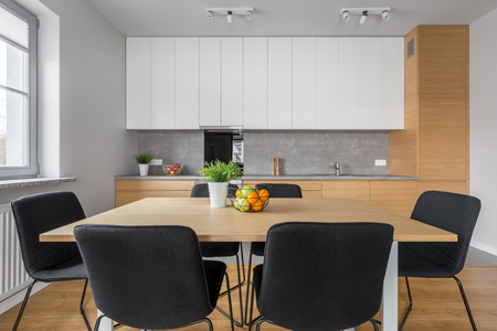 Modern design kitchen and dining area with wooden table, black chairs and ceiling lightの写真素材