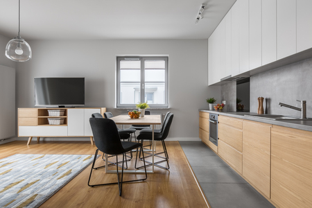 Modern apartment with open wood kitchen with table and long countertopの写真素材