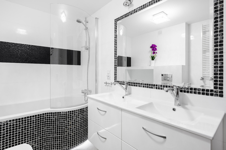 Black and white luxury bathroom with mosaic tiles, bathtub and mirrorの写真素材