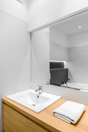 New, white bathroom with wooden cabinet, stylish basin and big mirrorの写真素材