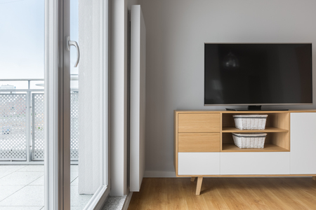 Tv living room with balcony, grey wall, wooden cabinet and floor panelsの写真素材