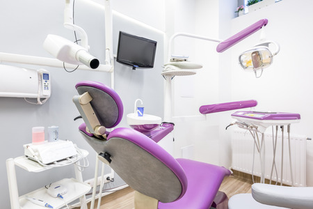 White interior with modern dental unit with violet chair, LED lamp and screenの写真素材