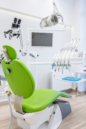 Professional dental clinic interior with modern, green chair, microscope, led lamp and screenの写真素材