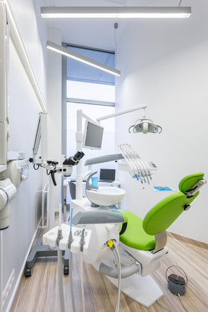 Modern dental clinic interior with green chair and professional toolsの写真素材