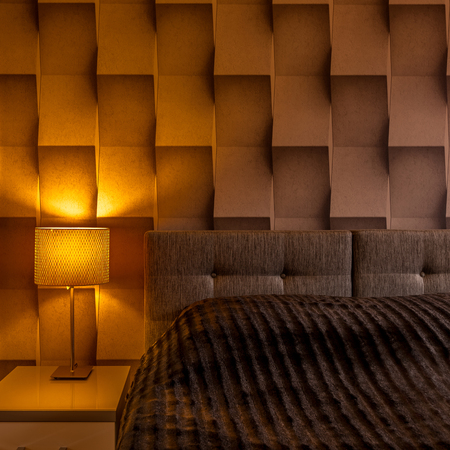Modern bedroom interior with big bed and geometric 3D wall texture  の写真素材