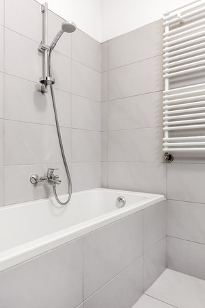 Simple built-in bathtub with gray tiles in home bathroomの写真素材