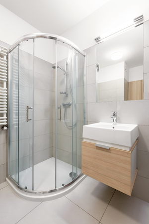 Shower and wooden cabinet for washbasin in home bathroomの写真素材