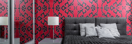 Cosy bedroom with big bed and patterned black and red wallpaper, panoramaの写真素材