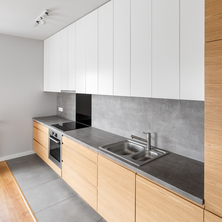 Contemporary kitchen with long, grey countertop and modern cupboardの写真素材