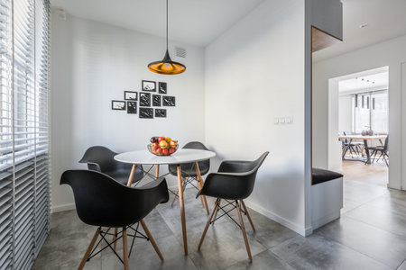 White home interior with lamp, modern round table and black chairs