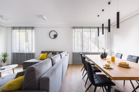 Modern home interior with communal table, black chairs and gray extra large sofaの写真素材