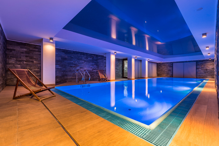 Luxurious indoor swimming pool and stylish, wooden deckchairsの写真素材