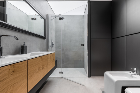 Modern, gray and black bathroom with shower, bidet, sink and wooden cabinetの写真素材