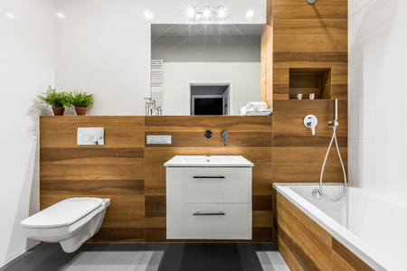 Modern, wooden bathroom with bathtub, mirror, toilet, cabinet and sinkの写真素材