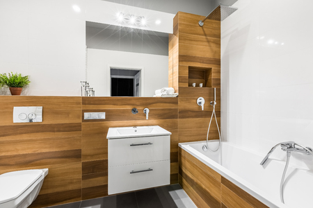 Modern, wooden bathroom with mirror, basin, toilet and bathtubの写真素材