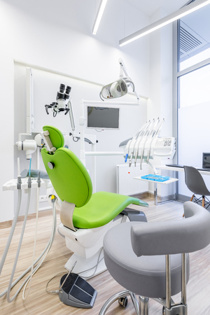 Modern dentist room with green chair and dental drillsの写真素材
