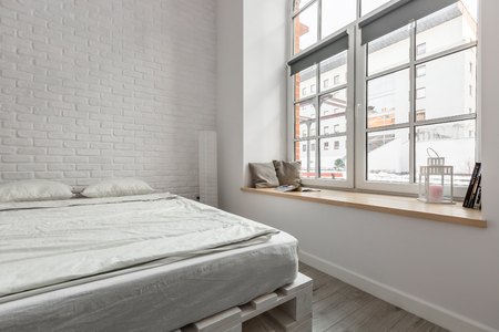 Loft bedroom with pallet bed and white brick wallの写真素材