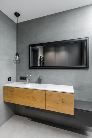 Gray bathroom with countertop basin, mirror and wooden cabinetの写真素材