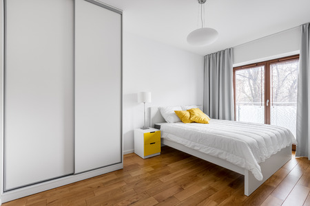 Modern bedroom with white wardrobe and double bedの写真素材