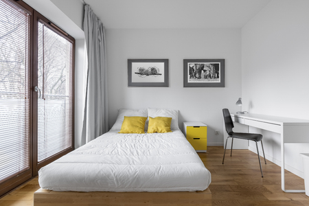 Functional, white bedroom with bed and modern, countertop deskの写真素材
