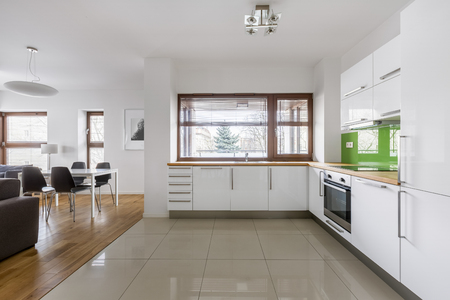 Modern apartment with open kitchen with white furniture and big windowの写真素材