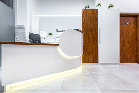 White interior with reception desk and wooden doorの写真素材