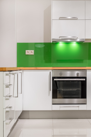 Kitchen with modern, white furniture, green backsplash and wooden worktopの写真素材