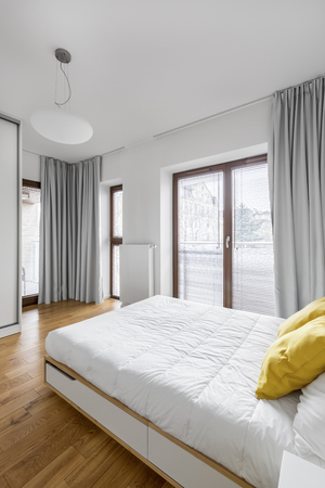White bedroom with double bed, big balcony windows and modern lampの写真素材