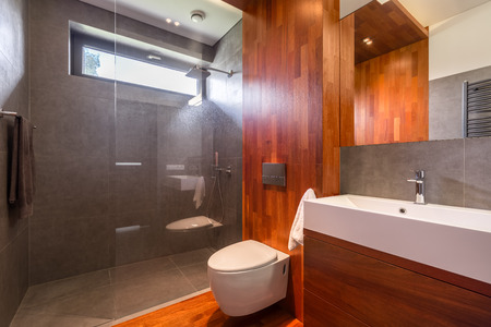 Luxurious wooden bathroom with shower, countertop basin, mirror and toiletの写真素材