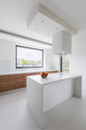 Modern, white kitchen with island and wooden cupboardsの写真素材