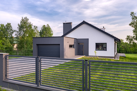 Stylish villa with fence, garage and lawn, exterior viewの写真素材