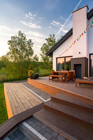 Exterior view of villa with patio with wooden flooring, furniture and stepsの写真素材