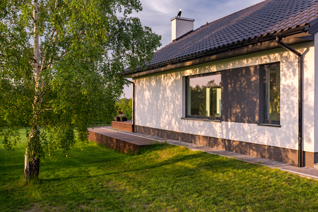 Cozy house with green lawn and tree, exterior viewの写真素材