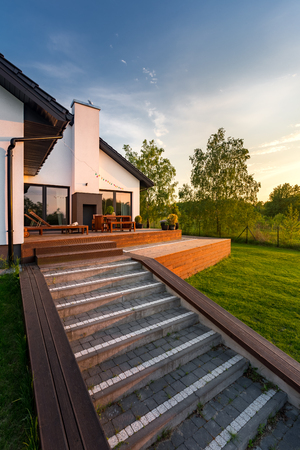 Exterior view of white house with wooden patio steps and green backyardの写真素材