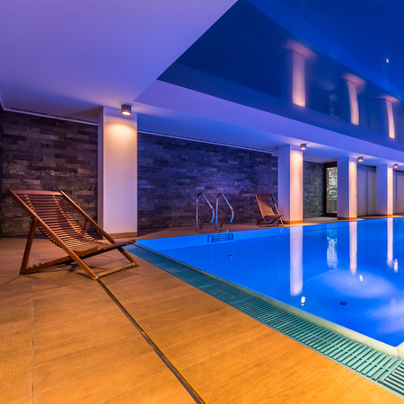 Luxurious indoor swimming pool and stylish, wooden deckchairsの写真素材