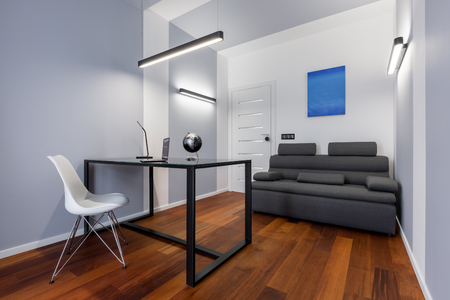 White home office with black table, white chair and gray couchの写真素材