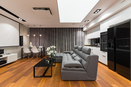 Home interior with sofa, table, projector screen and modern, open kitchenの写真素材