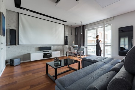 Gray and white living room with sofa, table, balcony and projector screenの写真素材