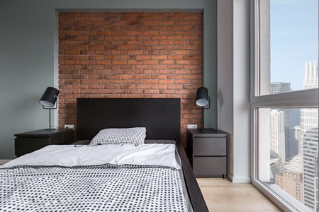 Simple bedroom with double bed, brick wall and big windowの写真素材