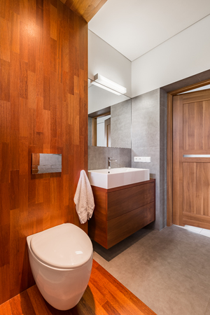 Wooden bathroom with toilet, mirror and cabinet basinの写真素材