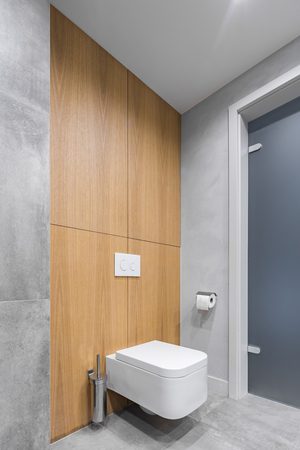 Gray bathroom with white toilet, and modern tiling with wooden detailsの写真素材