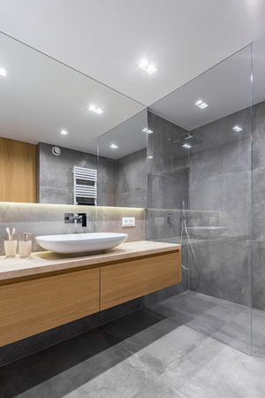 Gray bathroom with long countertop, mirror and walk in showerの写真素材