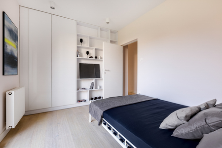White bedroom with wardrobe, bed, bookcase and modern artの写真素材