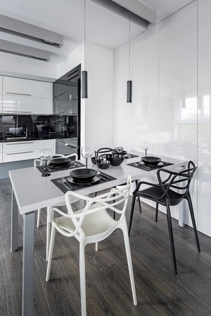 Home interior with white dining table, modern chairs and open kitchenの写真素材