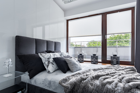 Modern bedroom with double bed, high gloss wall and big windowの写真素材